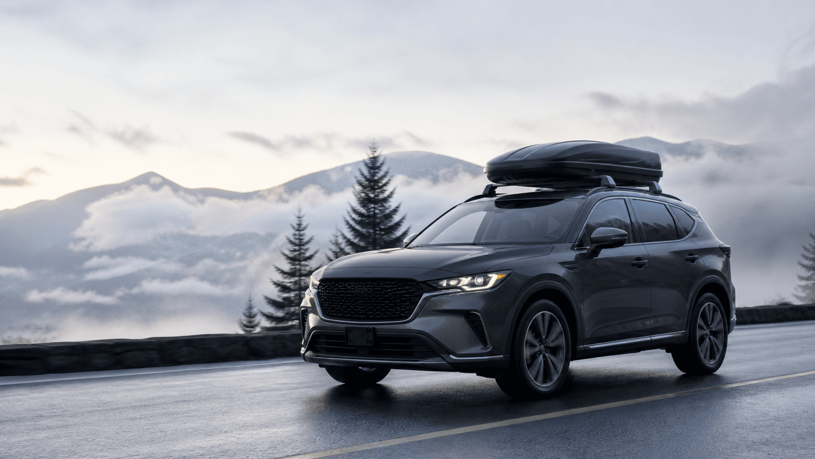 Generic rooftop cargo box mounted on a dark crossover on a mountain road
